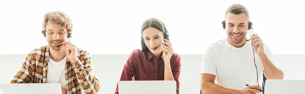 Plano panorámico de corredores felices en auriculares que trabajan en el centro de llamadas - foto de stock