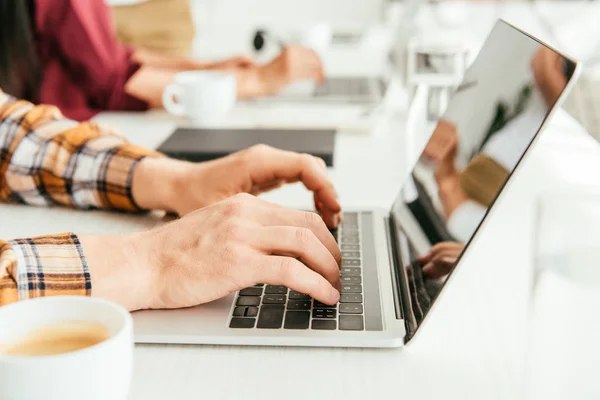 Selective focus of broker typing on laptop keyboard near woman in office — Stock Photo