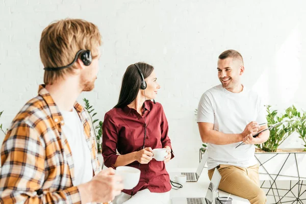 Selective focus of broker holding cup of coffee near coworkers in office — Stock Photo