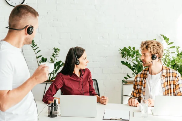 Fuoco selettivo di broker guardando l'un l'altro vicino collega con coppa — Foto stock