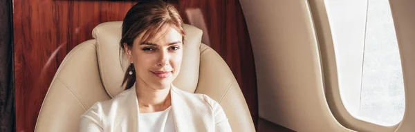 Colpo panoramico di attraente donna d'affari sorridente in aereo privato — Foto stock
