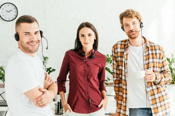 Happy brokers in headsets standing in office — Stock Photo