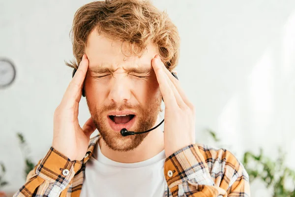 Tired broker suffering from migraine and touching head in office — Stock Photo