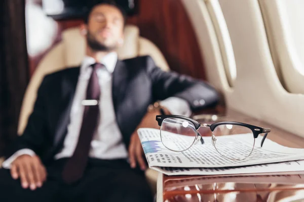 Selective focus of glasses and newspaper on table in private plane — Stock Photo