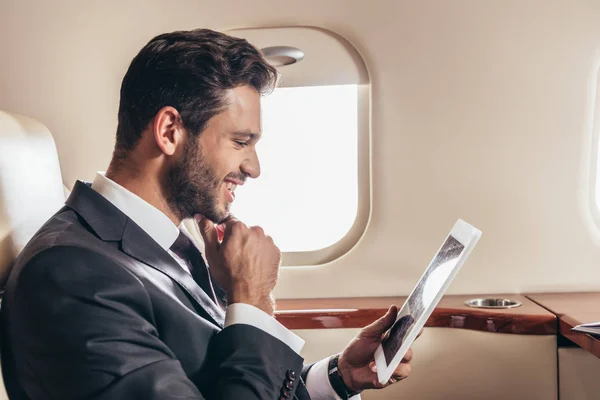 Bell'uomo d'affari in giacca e cravatta con tablet digitale in aereo privato — Foto stock
