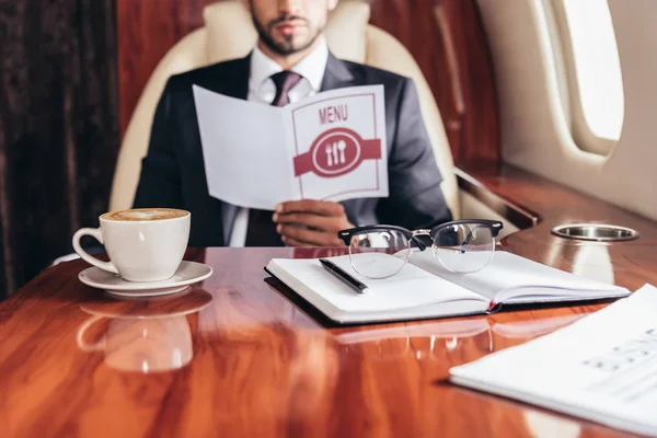 Selective focus of cup of coffee, notebook and glasses in private plane — Stock Photo