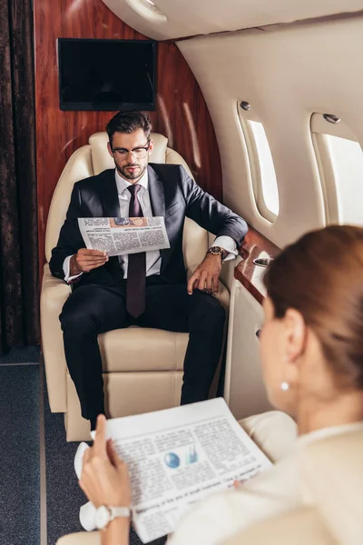 Foyer sélectif de l'homme d'affaires et de la femme d'affaires lisant le journal en avion privé — Photo de stock