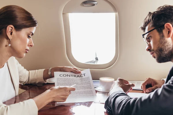Businessman and businesswoman looking at contract in private plane — Stock Photo