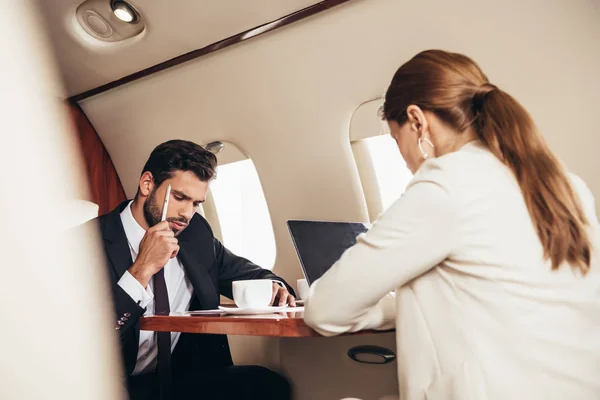 Selective focus of businessman and businesswoman working in private plane — Stock Photo