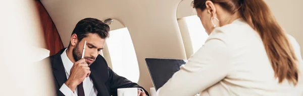 Panoramic shot of pensive businessman in suit in private plane — Stock Photo
