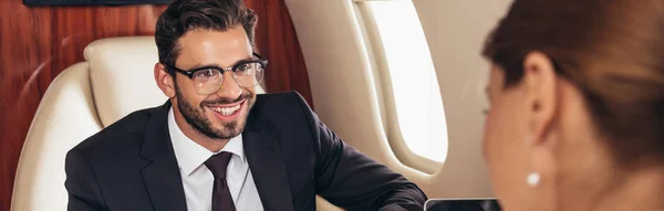 Foyer sélectif de sourire homme d'affaires regardant femme d'affaires en avion privé — Photo de stock