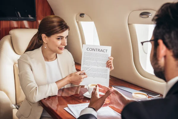 Attraente donna d'affari che mostra contratto per uomo d'affari in aereo privato — Foto stock