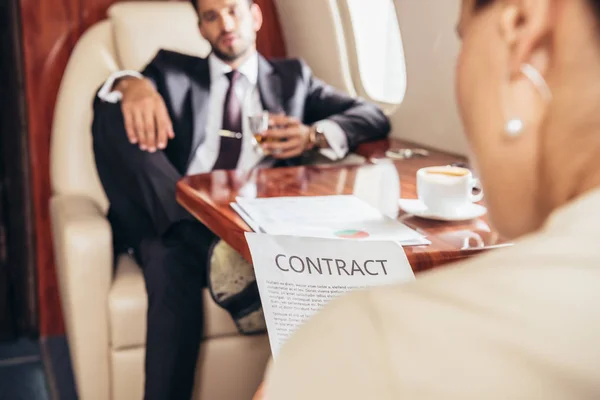 Selective focus of businesswoman reading contract in private plane — Stock Photo
