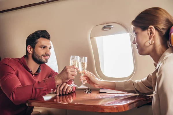 Novio y novia tintineo con copas de champán en avión privado - foto de stock