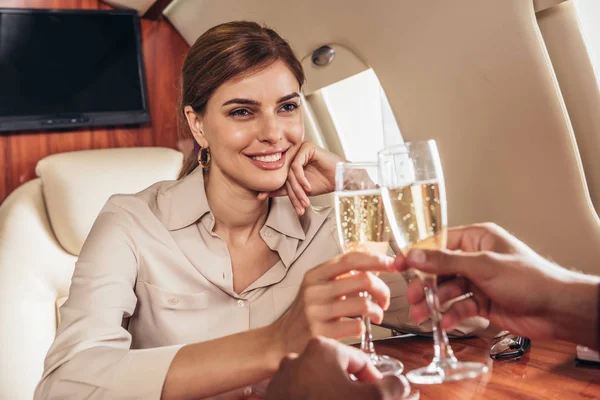 Бойфренд и улыбающаяся девушка звонят в бокалах для шампанского в частном самолете — стоковое фото