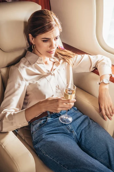 Привлекательная женщина в футболке с бокалом шампанского в частном самолете — стоковое фото