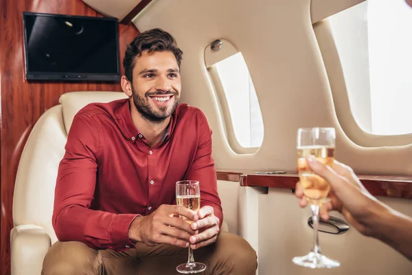 Petit ami souriant et petite amie tenant des verres de champagne dans un avion privé — Photo de stock