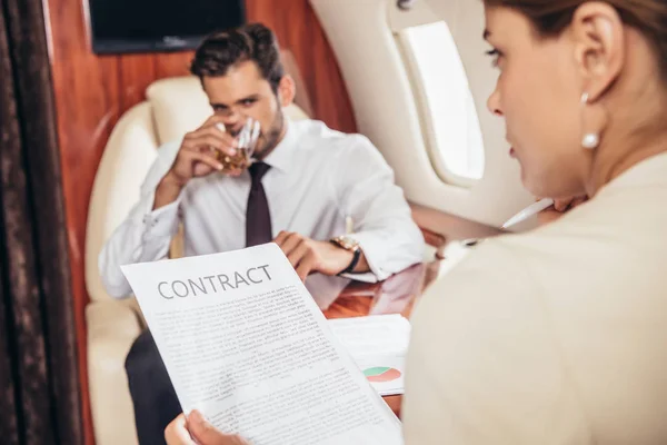 Selective focus of businesswoman holding contract in private plane — Stock Photo