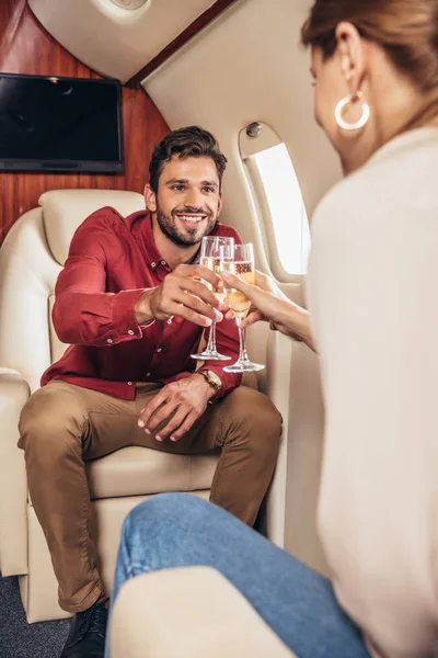 Улыбающиеся бойфренд и девушка звонят с бокалами шампанского в частном самолете — стоковое фото