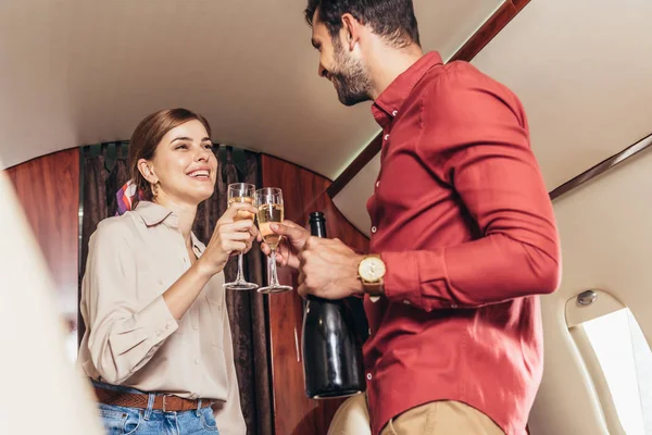 Парень и девушка звонят в бокалах для шампанского в частном самолете — стоковое фото