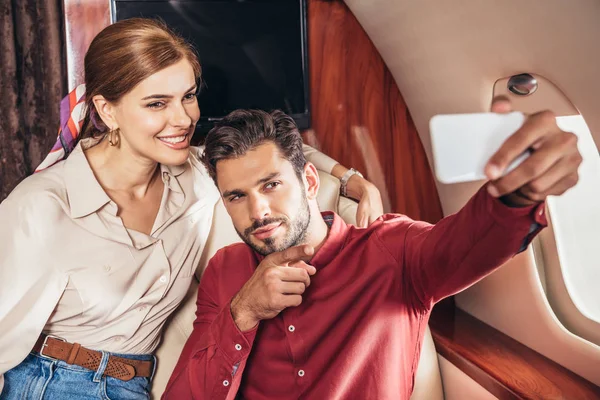 Селективное внимание парня и девушки, говорящих селфи в частном самолете — стоковое фото