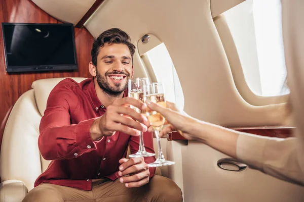 Fidanzato sorridente e fidanzata clinking con bicchieri di champagne in aereo privato — Foto stock