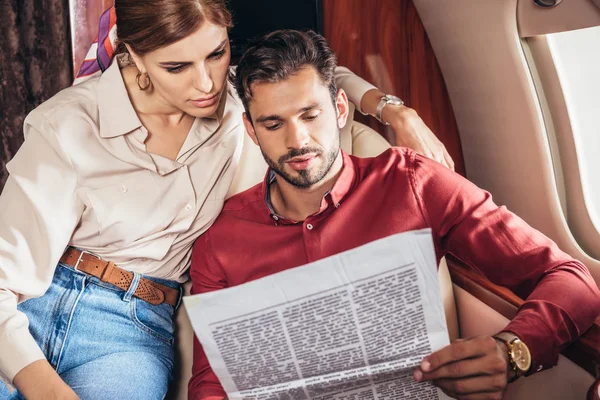 Красивый парень и девушка читают газету в частном самолете — стоковое фото
