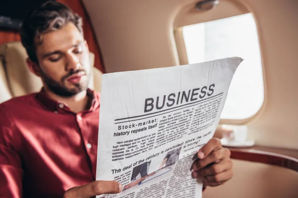 Hombre guapo en camisa leyendo periódico de negocios en avión privado - foto de stock