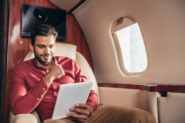 Schöner Mann im Hemd mit digitalem Tablet im Privatflugzeug — Stockfoto