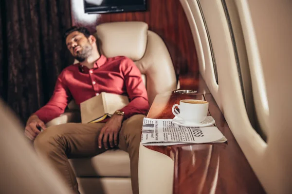 Homem bonito na camisa dormindo com livro em avião privado — Fotografia de Stock