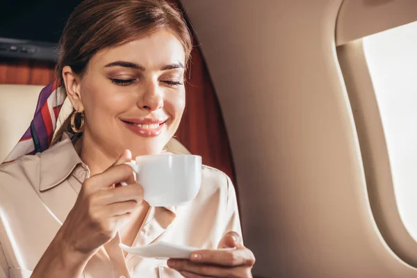 Mulher sorridente na camisa segurando xícara de café no avião privado — Fotografia de Stock