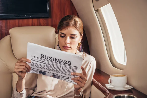 Attraente donna in camicia lettura giornale affari in aereo privato — Foto stock