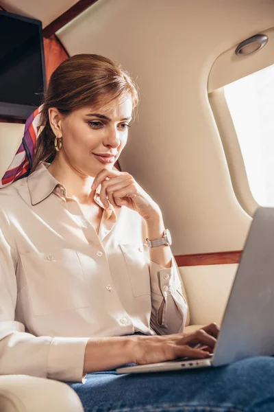 Attraktive Frau im Hemd mit Laptop im Privatflugzeug — Stockfoto