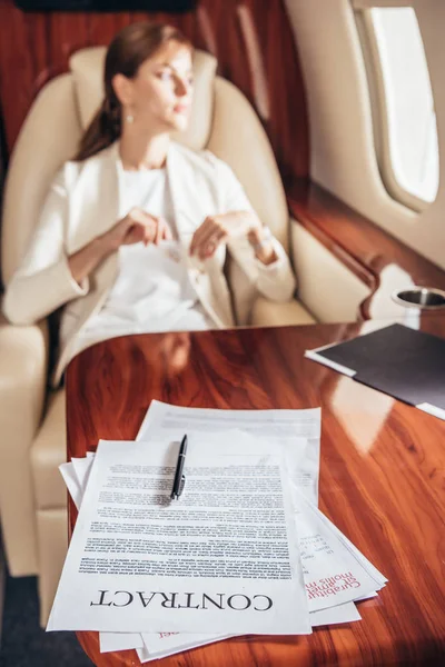 Selective focus of contract and pen on wooden table in private plane — Stock Photo