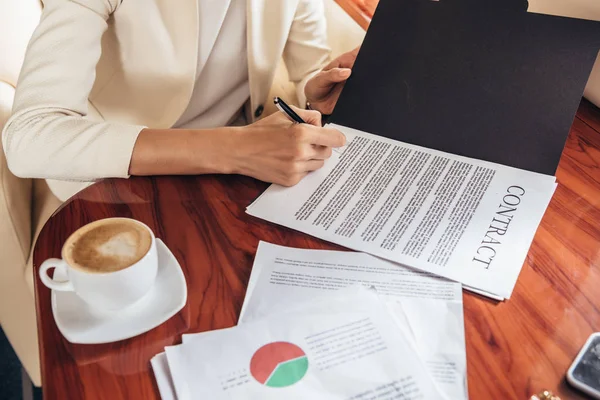 Cropped view of businesswoman in suit signing contract in private plane — Stock Photo