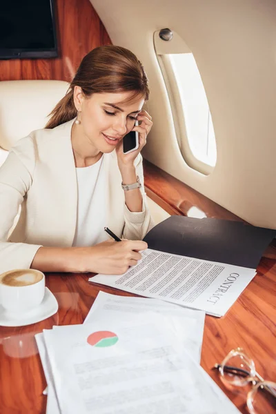 Attractive businesswoman in suit signing contract in private plane — Stock Photo