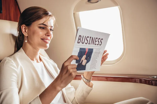 Atractiva mujer de negocios en traje de lectura de lectura de periódicos de negocios en avión privado - foto de stock