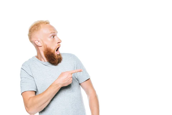 Schockierter bärtiger Mann im grauen T-Shirt zeigt vereinzelt auf Weiß — Stockfoto