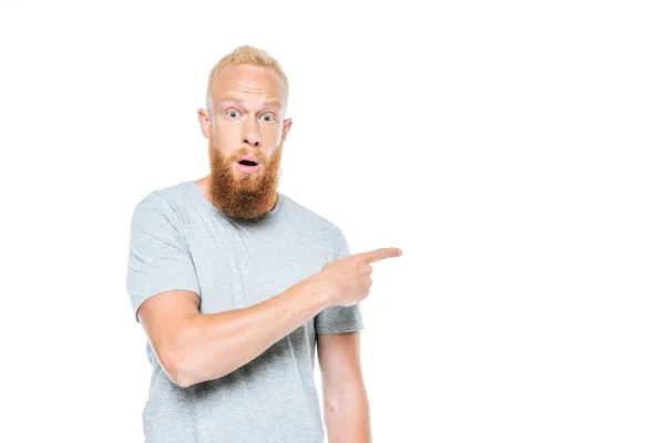 Красивий бородатий шокований чоловік у сірій футболці, вказуючи ізольовані на білому — стокове фото