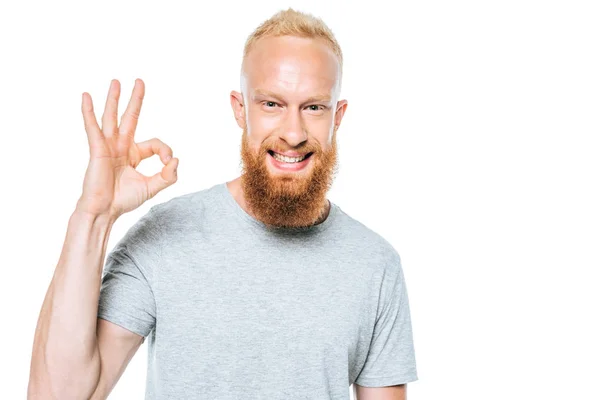 Hombre sonriente en camiseta gris que muestra signo ok, aislado en blanco - foto de stock