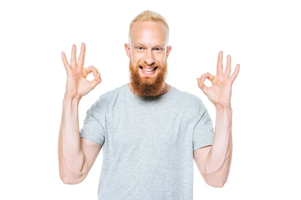 Bonito sorridente homem no cinza t-shirt mostrando ok sinais, isolado no branco — Fotografia de Stock