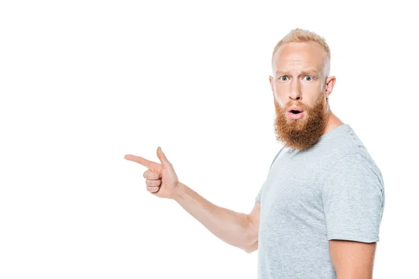 Schockierter bärtiger Mann im grauen T-Shirt zeigt vereinzelt auf Weiß — Stockfoto