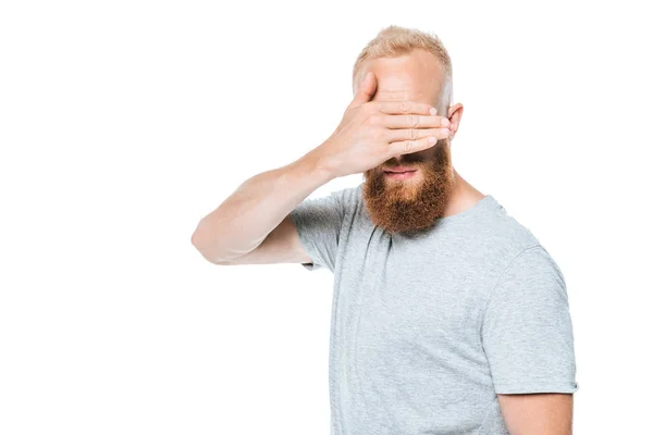 Красивий бородатий чоловік у сірій футболці закриває очі, ізольований на білому — стокове фото