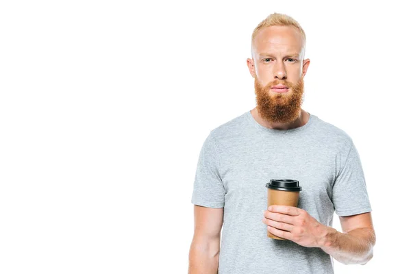 Hombre barbudo serio en camiseta sosteniendo café para llevar, aislado en blanco - foto de stock