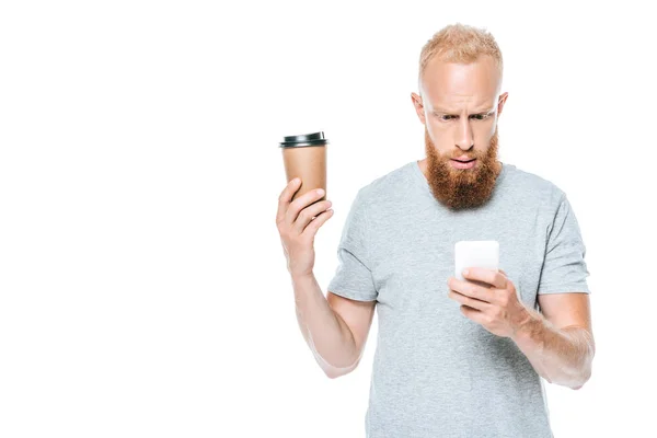 Homme barbu inquiet avec du café pour aller parler sur smartphone, isolé sur blanc — Photo de stock