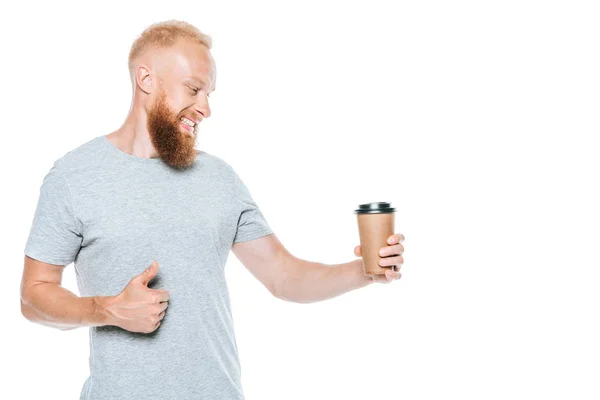 Smiling bearded man looking at coffee to go and showing thumb up, isolated on white — Stock Photo