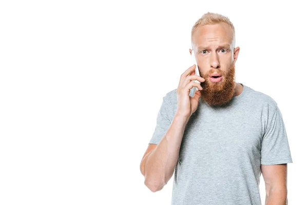 Шокований бородатий чоловік говорить на смартфоні, ізольований на білому — стокове фото