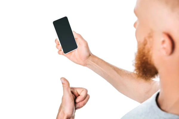 Vista recortada del hombre sosteniendo el teléfono inteligente con pantalla en blanco y mostrando el pulgar hacia arriba, aislado en blanco - foto de stock
