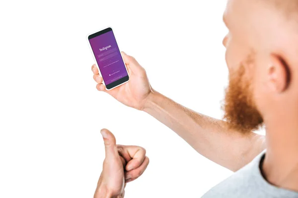 KYIV, UKRAINE - AUGUST 27, 2019: cropped view of man showing thumb up and looking at smartphone with instagram app, isolated on white — Stock Photo