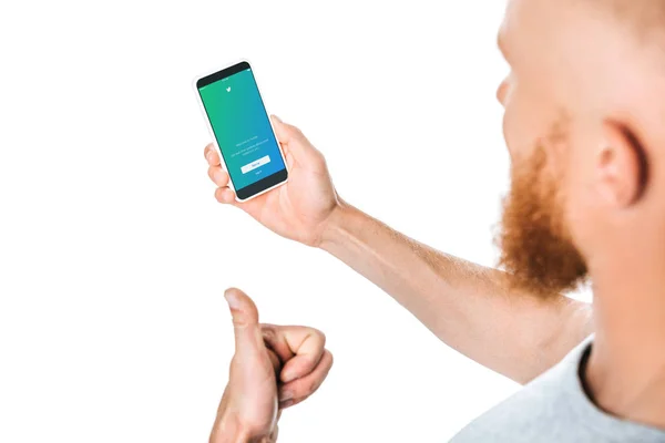 KYIV, UCRANIA - 27 de agosto de 2019: vista recortada del hombre mostrando el pulgar hacia arriba y mirando el teléfono inteligente con la aplicación de twitter, aislado en blanco - foto de stock